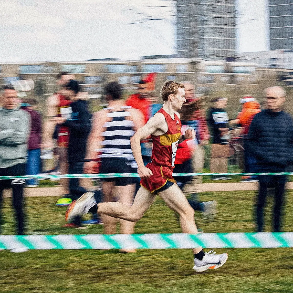 Matt mid-stride in a red and gold vest, panned against a blurred crowd.